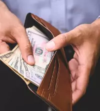 A man opening his wallet and pulling out cash
