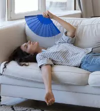 A woman trying to fight the heat by fanning herself, and struggling with summer depression