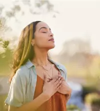 A woman holding her chest and deep breathing while practicing mindfulness